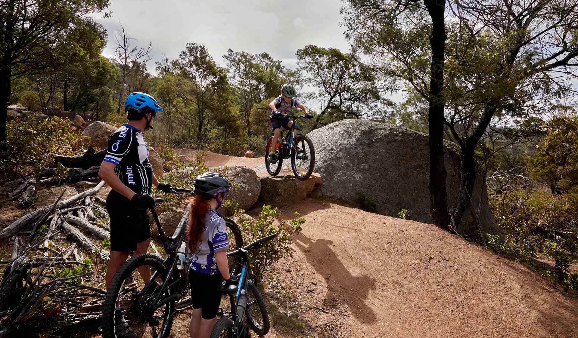 A young boy riding his bike in the Stockyards mountain bike area with his father and sister watching