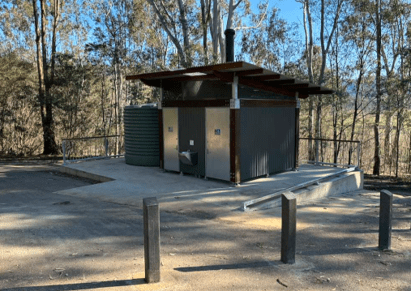 New public toilet facility at the main ramp, showing accessible design, metal-clad construction, water storage tank, concrete access paths, and surrounding bushland environment.