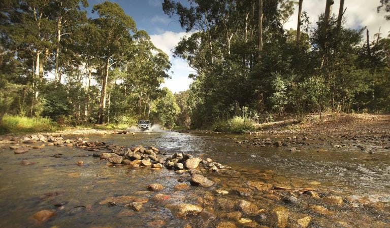 A four wheel drive crosses the Howqua River in the Alpine National Park.