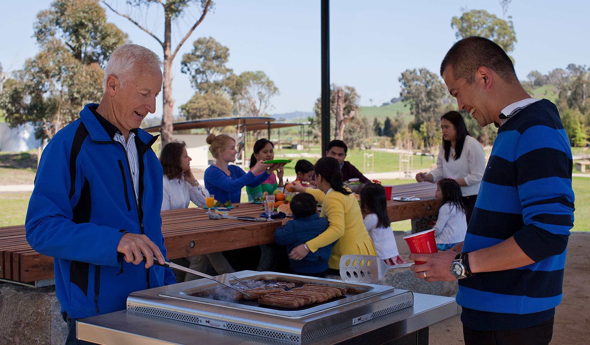 Two men cook share the cooking of a barbecue.