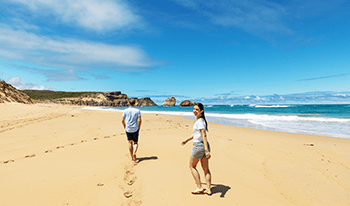 A girl looks back at the camera while walking along Sandy Beach in Bay of Islands Coastal Park