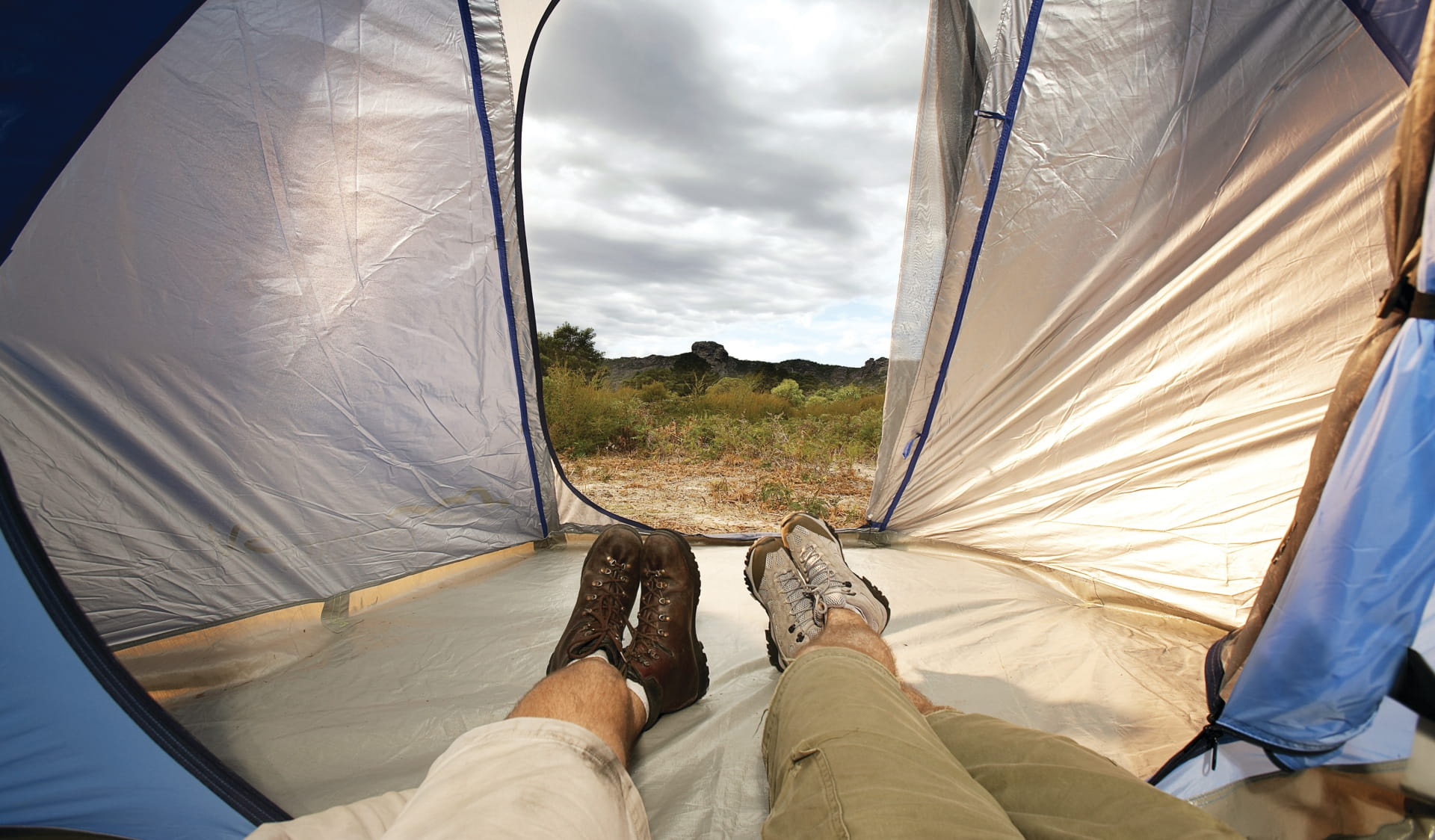 The view from inside a tent, looking out to the grassy landscape and cloudy sky.