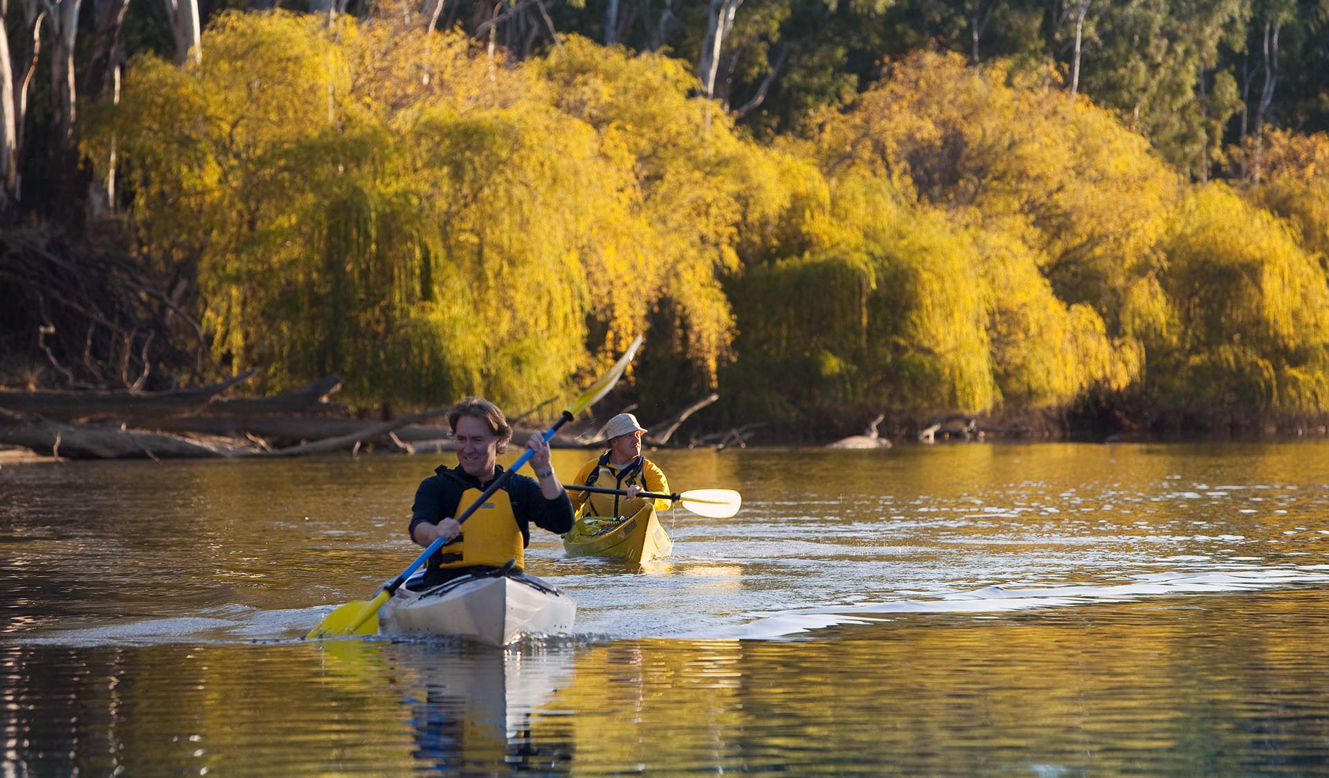 Two friends kayak along the river late in the afternoon.