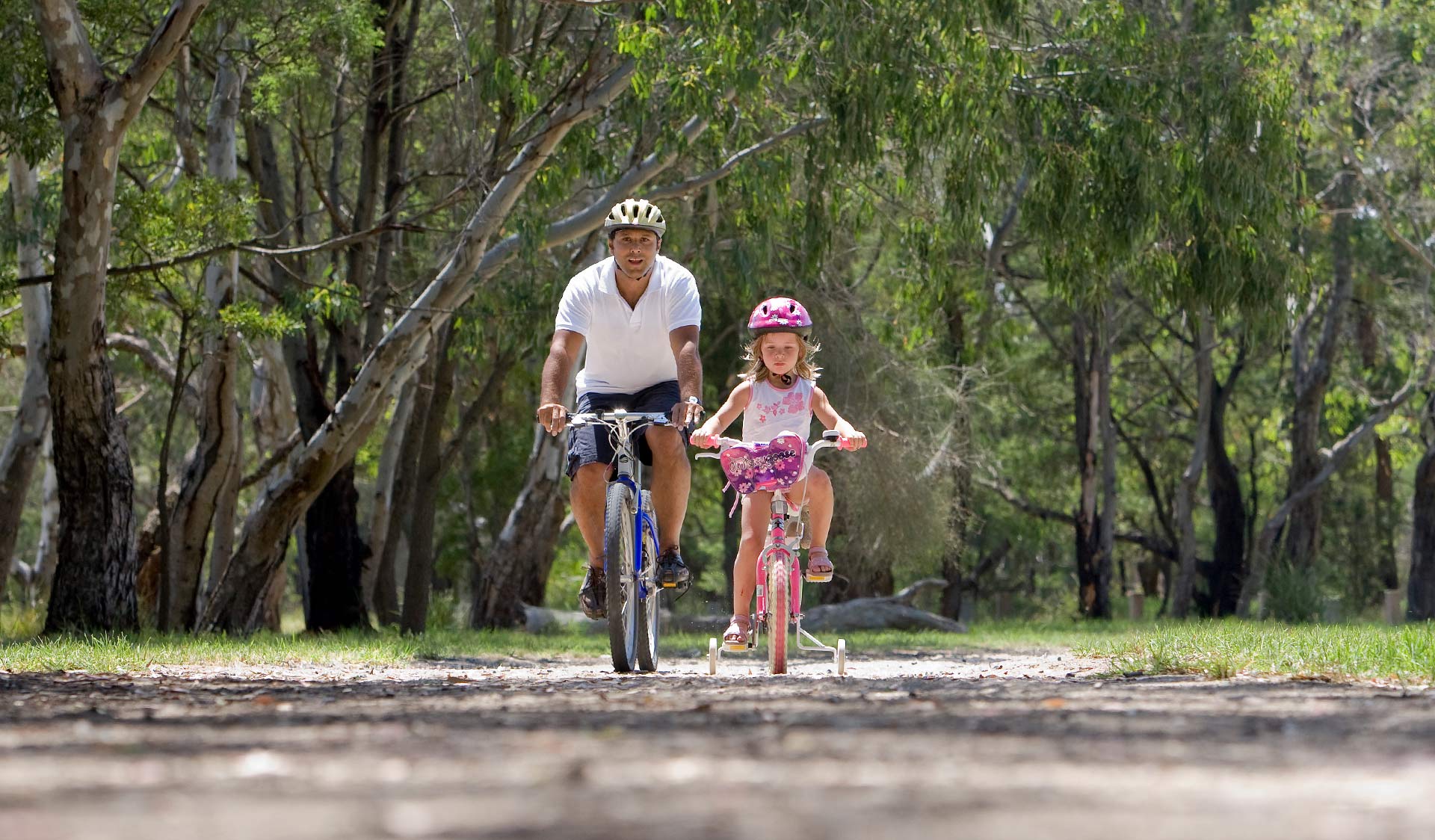 A father teaches his young daughter to ride a bike in Braeside Park.