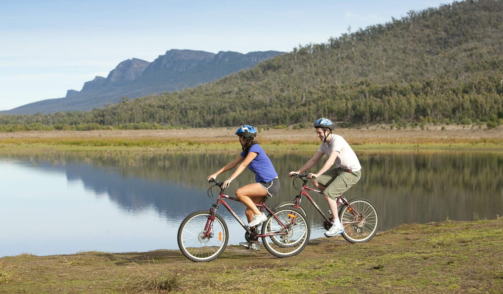 Two cyclists leisurely cycle around Lake Bellfield in the Grampians National Park.
