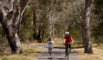 A woman on a bike and a child on a scooter at Jells Park