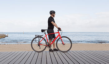 A man stands with his bike on a beach boardwalk in Melbourne