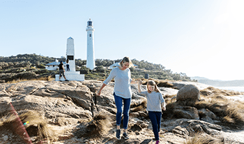 A mother and daughter walk over the rocks at Point Hicks Lighthouse in Croajingolong National Park