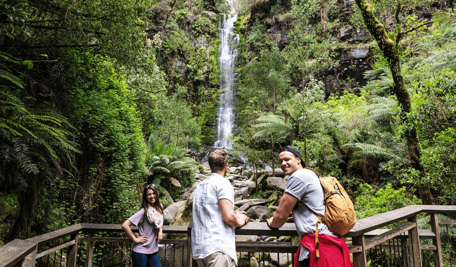 Three people standing at the viewing platform in rainforest.