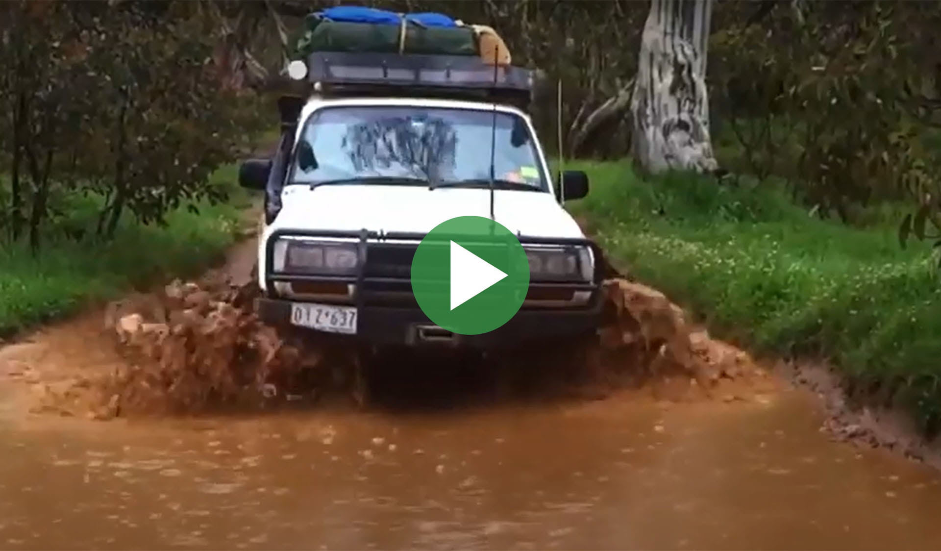 Still image from video of a 4wd driving through water with play icon overlay